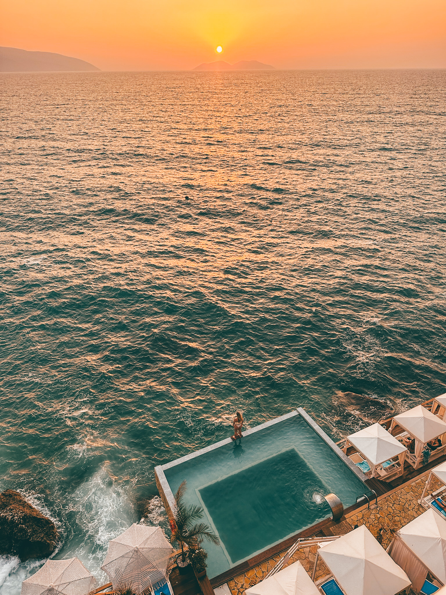 Aerial view of a cliffside infinity pool overlooking the Mediterranean Sea at sunset
