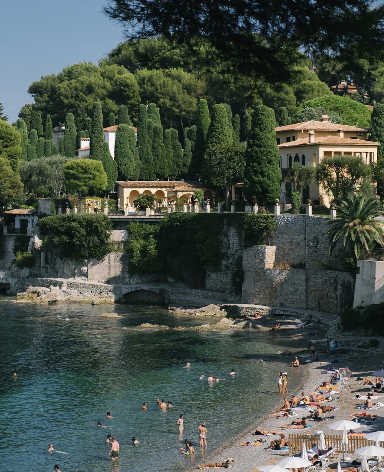 A secluded cove along the French Riviera, with a cypress-lined villa overlooking the turquoise water