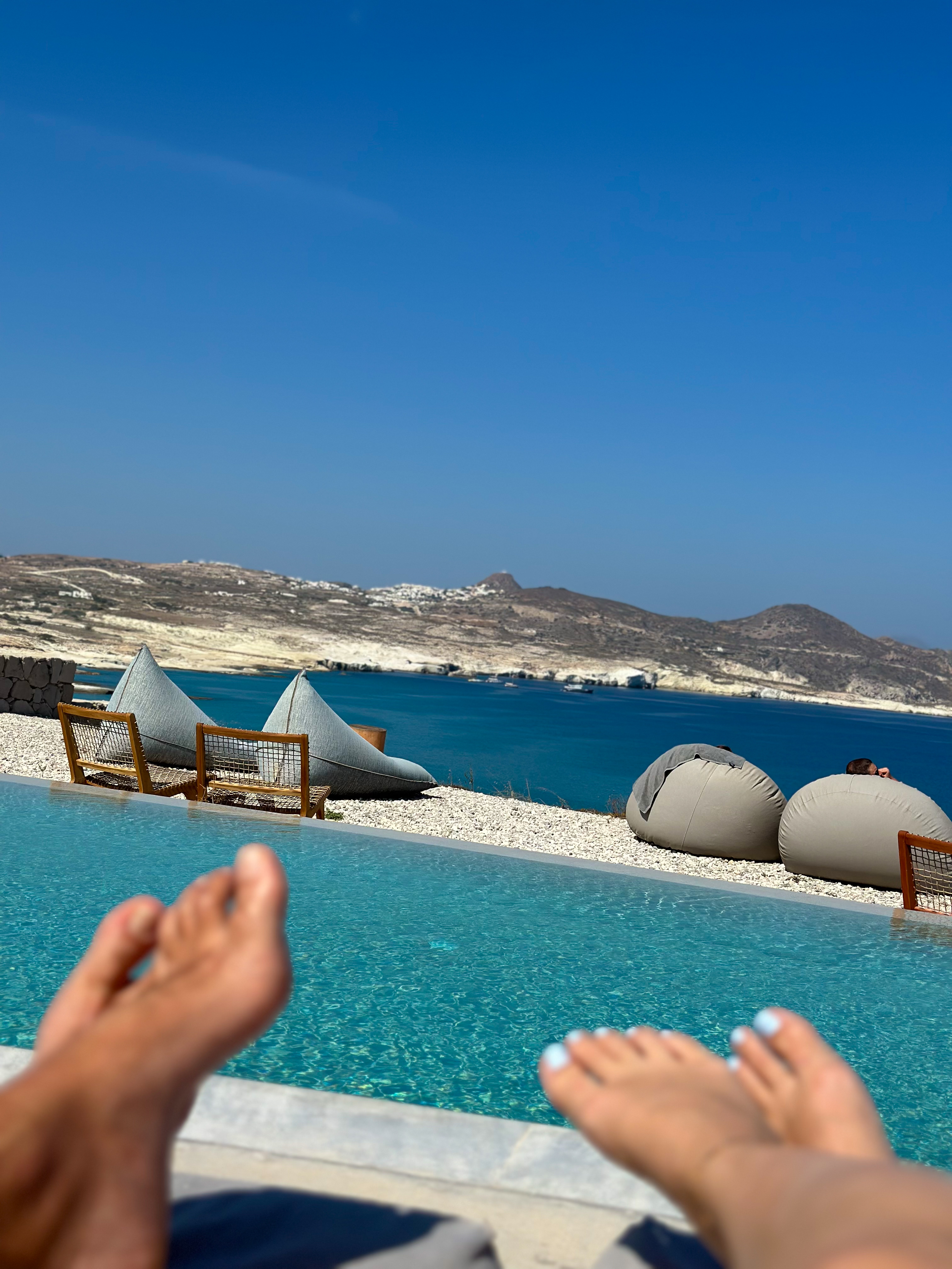 A view from a poolside lounger overlooking the hills and sea of the Greek islands