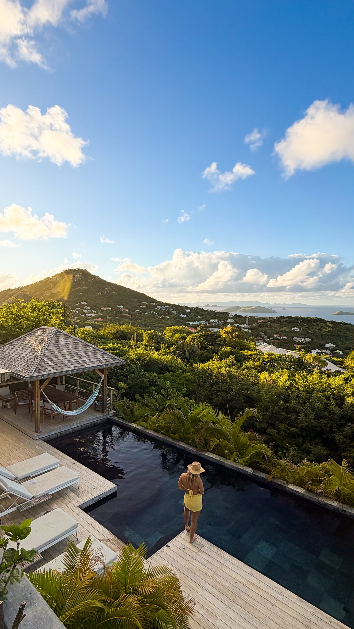 A traveler taking in the golden-hour view from a private infinity pool overlooking the hills and sea of St. Barths