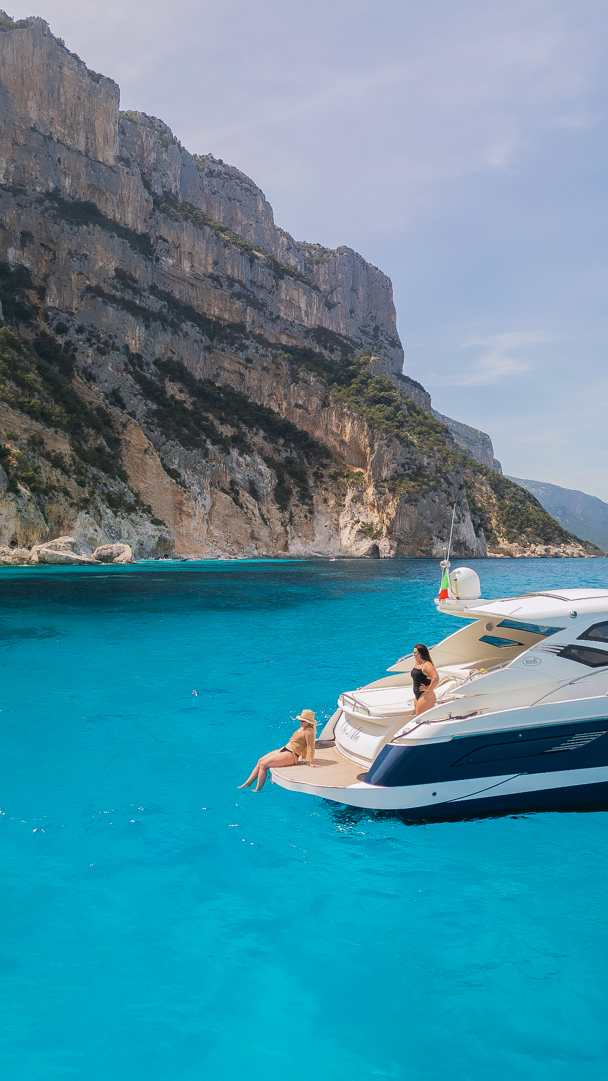 Two travelers relaxing on a private yacht along the cliffs of Sardinia, Italy