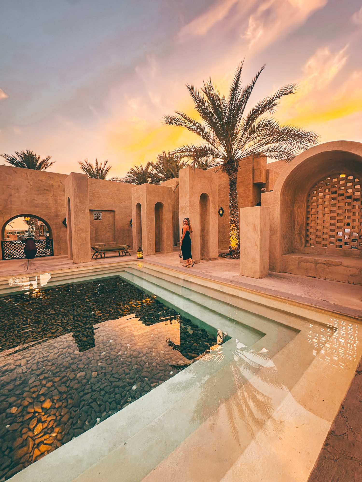 A traveler beside the pool of a desert riad in Morocco at golden hour