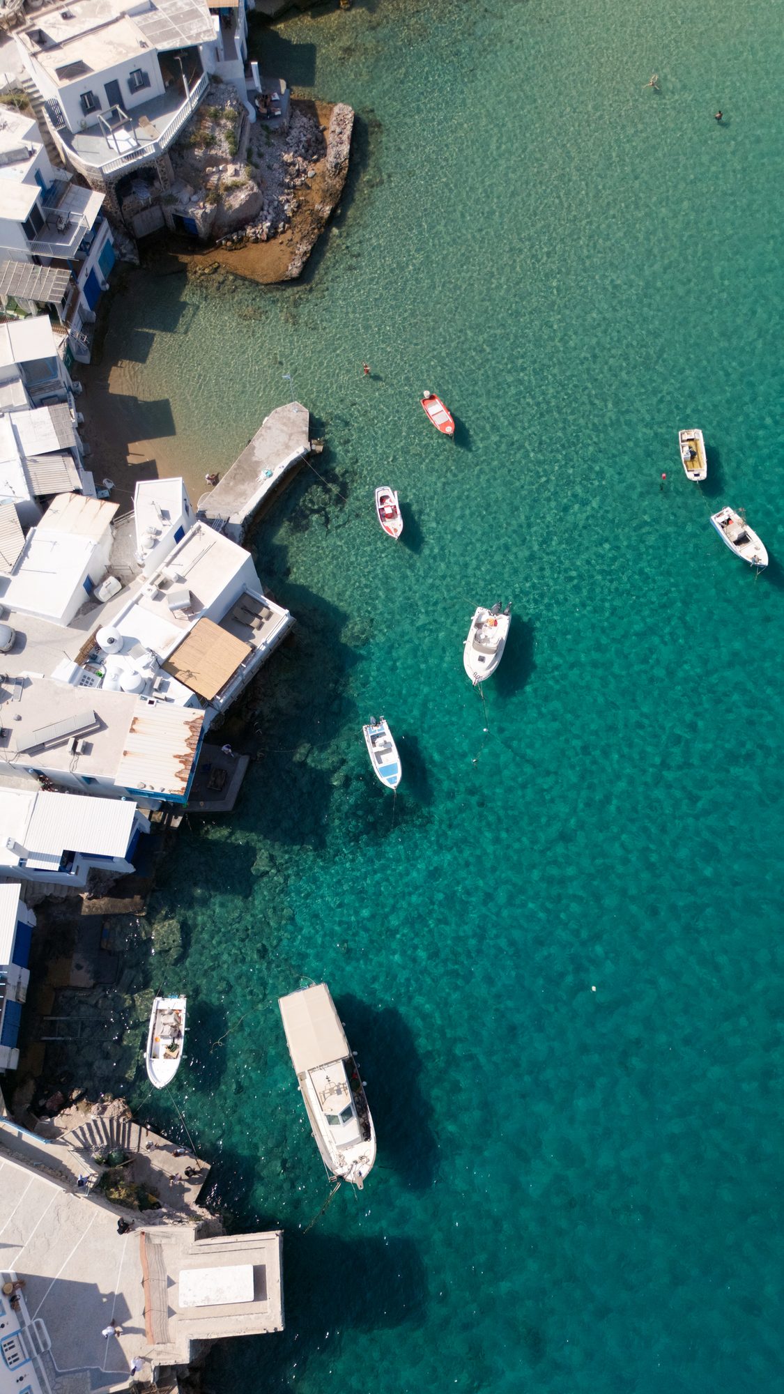 Aerial view of boats anchored in a turquoise harbor along the coast