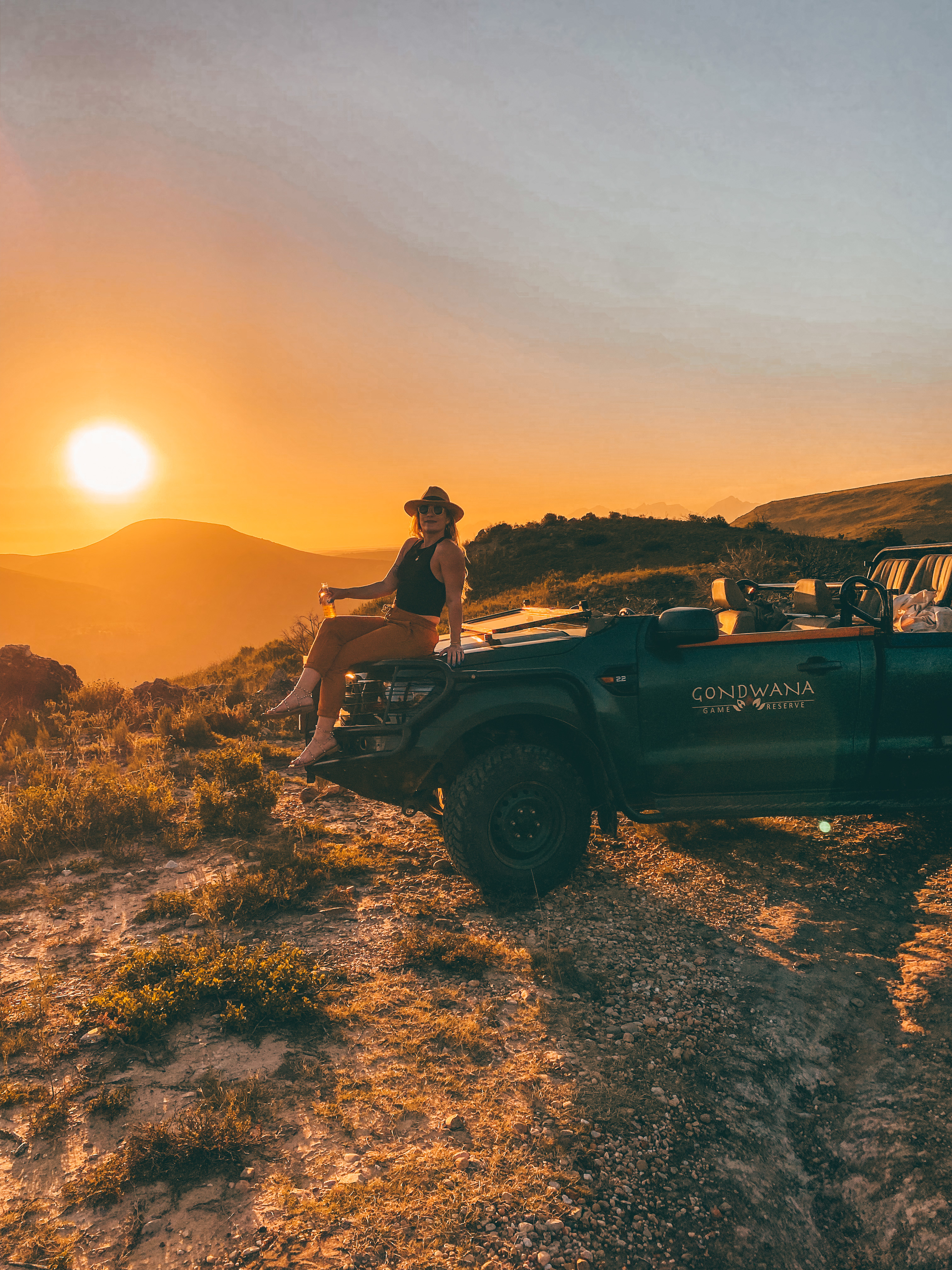 A traveler watching the sunset from an open-air safari vehicle at a South African game reserve