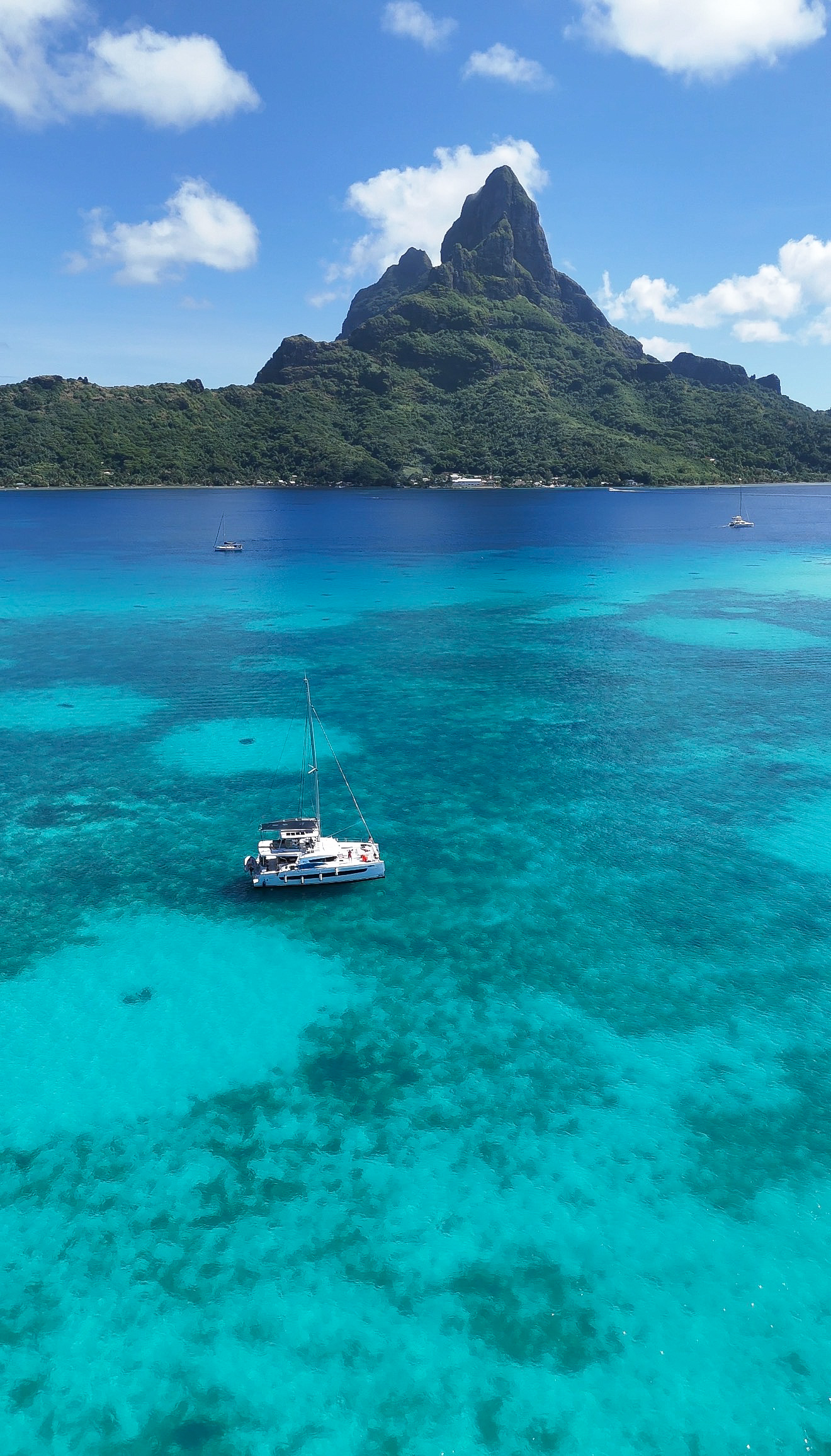 A catamaran anchored in the turquoise lagoon of Bora Bora, with the island's peak rising in the background